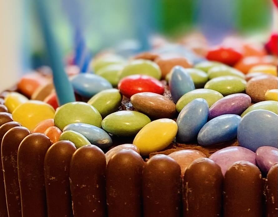 Chocolate cake decorated with chocolate finger biscuits and multi-coloured smarties on top
