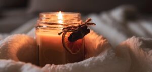 Candle burning in jar with orange and cinnamon decorations