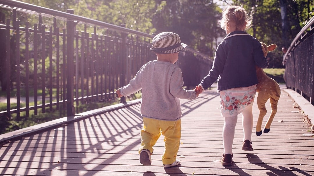 Two children crossing footbridge in park