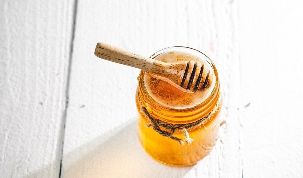 jar of honey on white wooden table